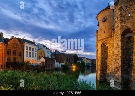 Abendlicher Blick auf das mittelalterliche Gravensteen-Schloss in der Dämmerung, das sich im Wassergraben in der historischen Altstadt von Gent, Belgien, spiegelt. Stockfoto