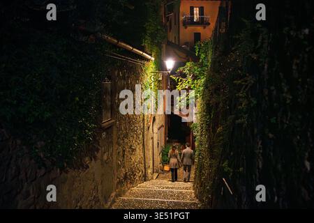 Ein junges Paar geht nachts eine schmale Treppe hinunter im Dorf Bellagio, Italien, am Comer See. Stockfoto