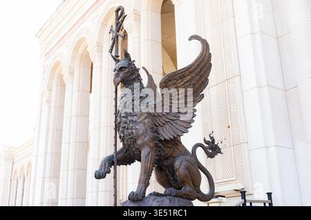 22. August 2025, New Chersonesus, Sewastopol, Russland. Eine Statue eines Löwen mit Flügeln und Stab. Männer stehen vor der Statue. Stockfoto