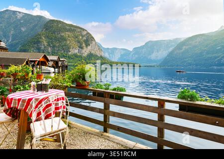 Ein kleines Café am Seeufer mit hölzernen Bootshäusern, einem Boot im Wasser und der dahinter liegenden Burg GRUB-Kaste am Hallstättersee, Österreich. Stockfoto
