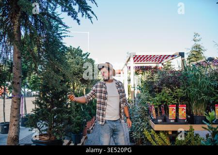 Mitarbeiter im Gartengeschäft, der sich um Pflanzen kümmert. Stockfoto
