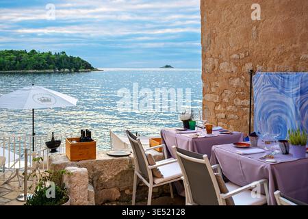 Ein farbenfroher Tisch in einem Restaurant am Meer in der Abenddämmerung in Rovinj, Kroatien. Stockfoto