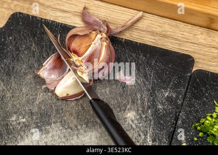Kreative Collage-Komposition mit mehrschichtigen gedruckten Seiten, roter Tomate, weißem Garn und strukturiertem Stoff auf einem Holztisch. Das Bild überblendet alles Stockfoto