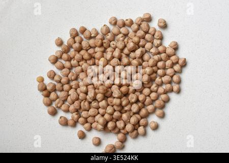 Getrocknete Kichererbsen auf einem sauberen, weißen Tisch, gefangen in sanftem Tageslicht. Minimale Zusammensetzung hebt gesunde Leguminosen hervor, pflanzliches Protein Stockfoto