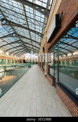 Innenansicht einer modernen Galerie mit großer Industrieglasdecke, Backsteinfassaden, Glasgeländern und hellem Fußboden Stockfoto