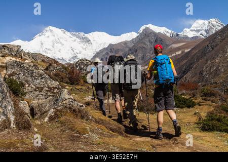 Zwei Trekker halten an, bevor Sie auf dem Gokyo Trail in der nepalesischen Region Khumbu ein riesiges schneebedecktes Himalaya-Panorama genießen. Stockfoto