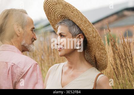 Alte Frau mit kurzen grauen Haaren, die einen Strohhut trägt und ihren Mann ansieht Stockfoto