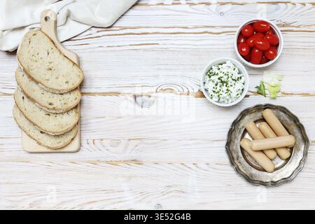 Frühstückstisch mit Hütte, Würstchen und Tomaten. Kopierraum, Holzhintergrund. Stockfoto