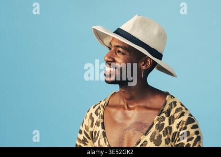 Glücklicher Mann in weißem Hut, der vor blauem Hintergrund steht und wegschaut Stockfoto