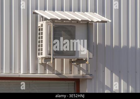 Externe Klimaanlage an der Fassade des Gebäudes aus profiliertem Blech unter einem Vordach auf einer tragenden Metallkonstruktion Stockfoto