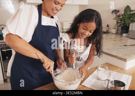 Das Mädchen und ihre Oma mischen den Teig in einer Glasschale Stockfoto