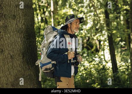 Älterer Mann mit Rucksack und Wanderkleidung, der im Wald spaziert Stockfoto