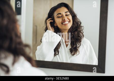 Schöne Frau aus dem Nahen Osten mit geschlossenen Augen davor Eines Spiegels Stockfoto