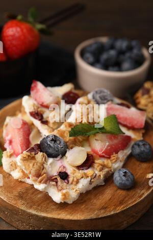Leckere Joghurtrinde mit Beeren, Minze und Müsli auf dem Tisch, Nahaufnahme Stockfoto