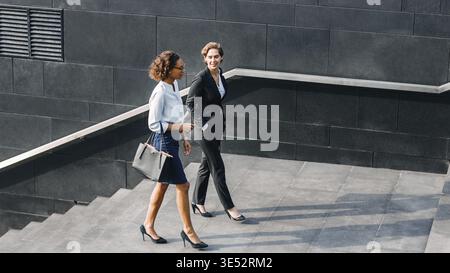 Zwei Frauen im Büro tragen Walking im Freien und im Gespräch Stockfoto