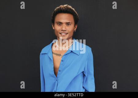 Porträt eines jungen, gutaussehenden Kerls, einer schwarzen Wand, die in die Kamera schaut Stockfoto