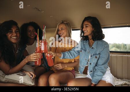 Eine Gruppe von verschiedenen Freundinnen, die ihren Urlaub feiern. Vier Frauen sitzen bei Cocktails Stockfoto