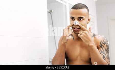 Junger Mann die Nase Patch vor einem Spiegel Stockfoto
