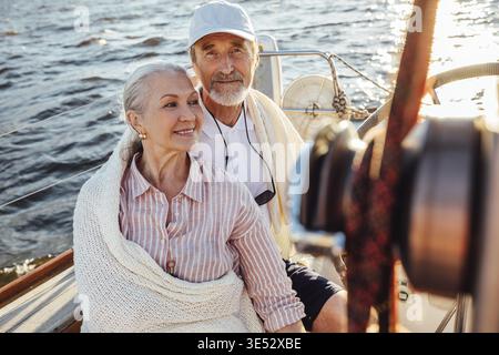 Ein reifes Paar sitzt auf einer Yacht und ist in eine weiße Decke gehüllt Stockfoto