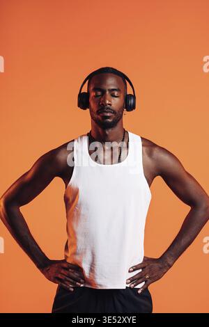 Afroamerikanischer Sportler, der Musik über kabellose Kopfhörer hört. Mann in Sportkleidung, der sich während des Fitnesstrainings entspannt Stockfoto