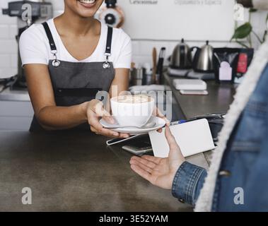 Nicht erkennbare Coffee Shop Besitzer übergeben, um eine Tasse Kaffee zu Ihren Kunden Stockfoto