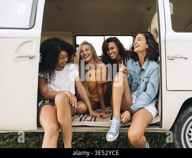 Multiethnische Gruppe von Frauen, die Spaß haben, während sie in einem Auto sitzen. Vier Freunde auf Reisen Stockfoto