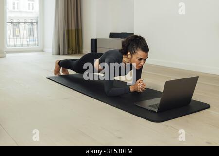 Junge fit Frau dabei Plank auf Matte zu Hause Stockfoto