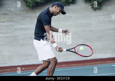 Junger Mann, der draußen Tennis spielt. Tennisspieler, der einen Ball schlägt Stockfoto