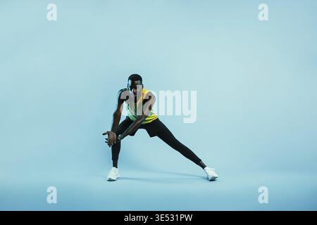 Männlicher Athlet, der Dehnungsübungen macht. Junger Mann in Sportkleidung, der Beine und Arme aufwärmt Stockfoto