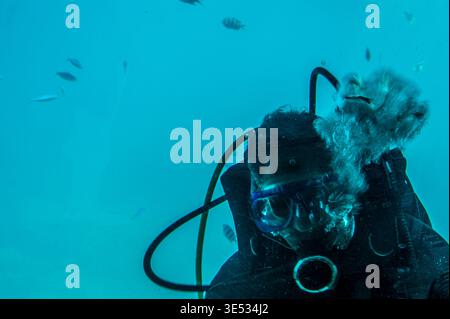Hurghada, Ägypten, 28. März 2026. Eine Unterwasseransicht aus nächster Nähe eines professionellen Tauchers, der durch das Panoramafenster eines Sea Scope Semi-Submas winkt Stockfoto