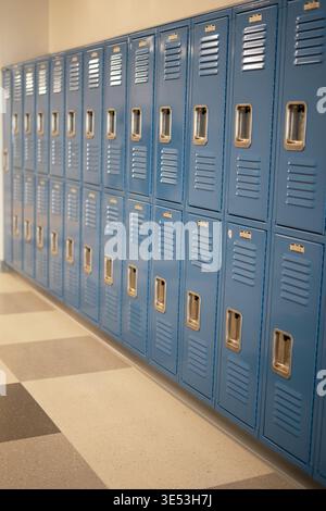 Reihe blauer Schulschränke im Flur mit perspektivischem Blick. Sauberer Bildungshintergrund mit Kopierraum und ohne Leute. Stockfoto