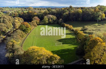 Luftaufnahme eines grünen Fußballfeldes, das vom River Swale und den Herbstbäumen in Richmond begrenzt wird Stockfoto