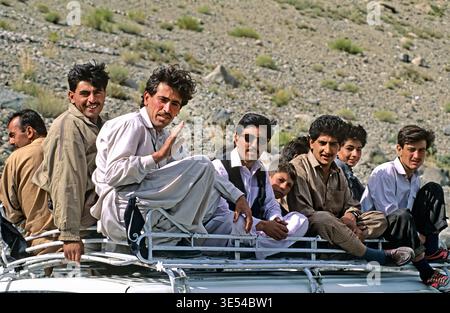Die Menschen reisen gerne auf dem Dach eines Kleinbusses, während sie die Berge Pakistans erkunden. Die Gruppe teilt gemeinsam Lächeln und Ansichten. Stockfoto
