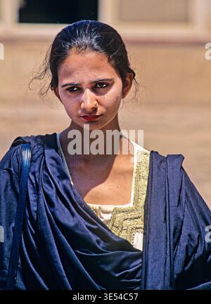 Eine Frau steht in Lahore in traditioneller Kleidung. Sie blickt mit einem ernsten Ausdruck direkt in die Kamera. Stockfoto