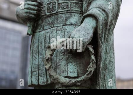 Nahaufnahme einer verwitterten Bronzestatue, die einen Lorbeerkranz hält, mit komplizierten Texturen, oxidierter Patina und klassischer römischer Militärkleidung Stockfoto