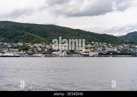 Bergen, Norwegen - 6. Juli 2024: Blick auf das industrielle Wasser und die Hügelhäuser in der Stadt Stockfoto