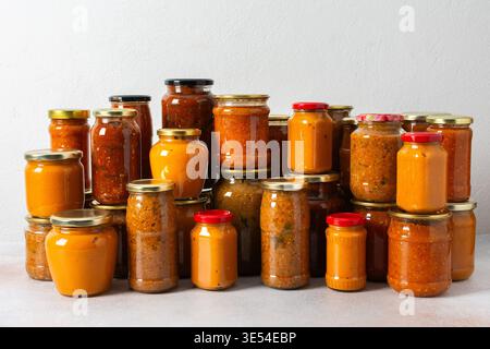 Verschiedene Gläser mit hausgemachtem Gemüse stehen zur Vorbereitung auf den Winter an. Die farbenfrohen Gläser zeigen eine Reihe von konservierten Lebensmitteln, die bereit sind Stockfoto