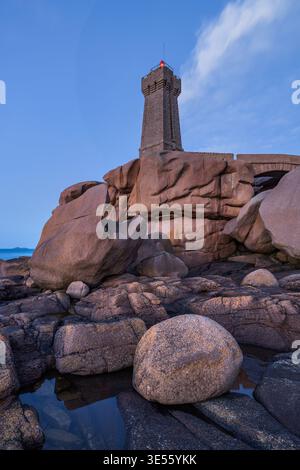 Blick auf den Leuchtturm von Ploumanac'h, der auf rosafarbenen Granitfelsen unter einem Dämmerungshimmel in Perros-Guirec, Bretagne, Frankreich steht. Stockfoto