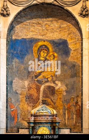 Nahaufnahme eines mittelalterlichen religiösen Freskos in Ruinen, die eine Mauer-Nische in der historischen Kirche in Rom schmücken Stockfoto