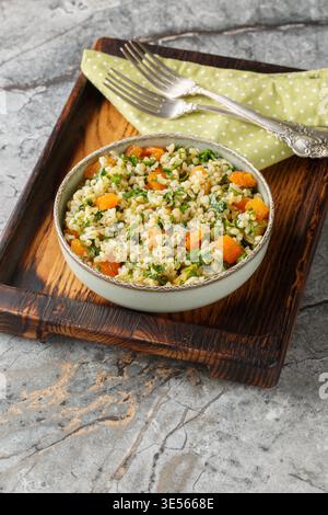 Bulgur-Salat mit Petersilie und getrockneten Aprikosen in einer Schüssel auf dem Tisch. Vertikal Stockfoto