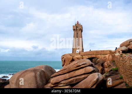 Der Leuchtturm Mean Ruz erhebt sich über seiner Granitbrücke in Tregastel, an der Pink Granite Coast in der Bretagne, Frankreich, mit Blick auf raue See und abgerundete Kanten Stockfoto