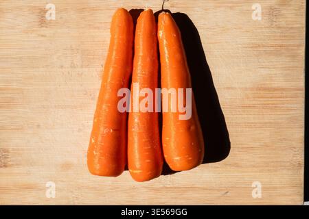 Gemischtes frisches Bio-Gemüse, einschließlich rote Tomaten, grüne Paprika und Orangenmohröhren, auf weißen Tellern und Holzschneidebrettern, M Stockfoto