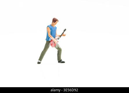 Miniatur-Gitarrist Figur spielt rote elektrische Gitarre auf weißem Hintergrund für Musikkonzept Stockfoto