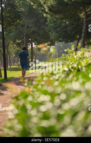 In einem grünen Stadtpark laufen Menschen entlang des Weges Stockfoto