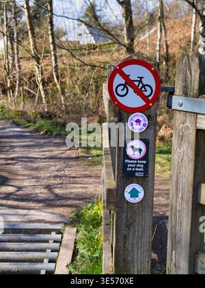 Derbyshire, UK - 26. März 2026: Holzpfosten am Wanderweg mit Schildern „Kein Radfahren“ und „Hund an der Leine“ neben einem Feldweg in Derbyshire, UK, helles Frühlingslicht und klare Details im Freien Stockfoto