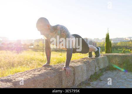 Tätowierter Mann, der im Freien Liegeübungen macht Stockfoto