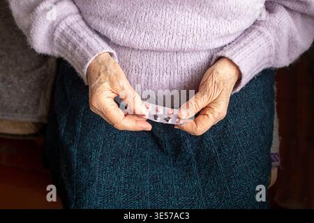 Ältere Frau mit Blisterpackung mit Pillen auf dem Schoß, Strickpullover und Rock Stockfoto
