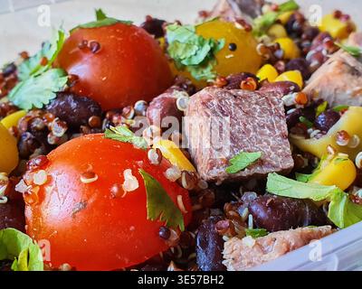 Nahaufnahme eines Makrofotos einer farbenfrohen, frischen Kornschale oder eines Salats. Das Gericht umfasst leuchtende rote Kirschtomaten, gelbe Kirschtomaten und schwarze Stockfoto