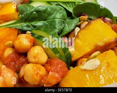 Nahaufnahme einer bunten, gesunden Buddha-Schüssel oder eines Salats mit gebratenem goldenem Butternusskürbis oder Kürbiswürfeln, Kichererbsen in reichhaltiger Tomate Stockfoto