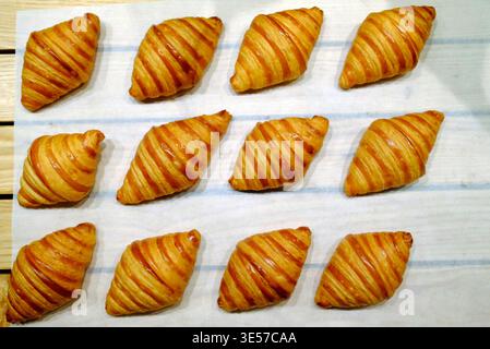 Frisch gebackene Buttercroissants auf einem Holztablett in einer Bäckerei. Vietnam. Stockfoto